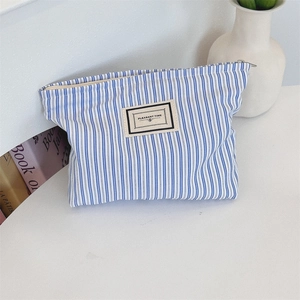 Close-up of blue striped canvas makeup bag with Pleasant Time label and metal zipper