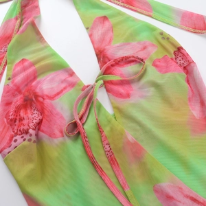 Close-up detail of green floral backless dress with halter neck strap and mesh texture