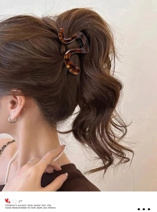 Detail shot of wavy amber tortoiseshell hair claw clip securing a sleek high ponytail