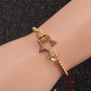 Détail d'un bracelet réglable en corde rouge avec pendentifs étoiles dorés et zircons
