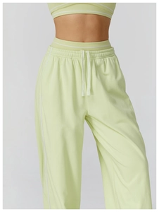 Détail d'un pantalon de sport vert clair à taille haute avec cordon et rayures latérales