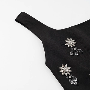 Détail de bretelles en tissu noir ornées de strass en forme de soleil et de cristaux