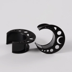 Detailed view of black stainless steel moon-shaped ear gauges with hollow filigree design