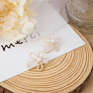 Detailed view of pearl flower stud earrings with gold metal base on a rustic wood background