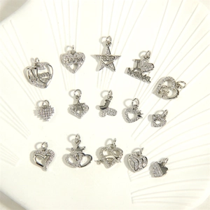 Assorted silver heart and star zircon charms on a white ceramic plate for DIY necklaces