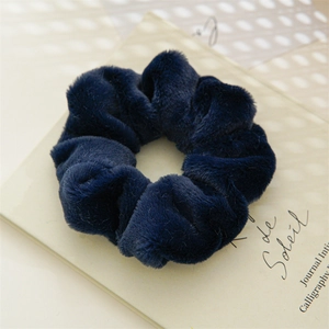 Close-up of soft navy blue plush faux rabbit fur hair scrunchie on vintage paper