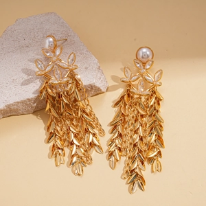 Macro shot of 18K gold plated pearl flower earrings with crystal leaf tassels on stone