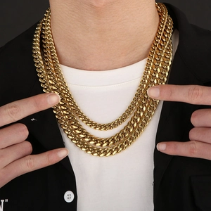 Three-layer stacked gold stainless steel Cuban link chains worn by a model on white shirt