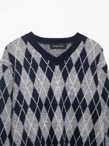 Detail of the V-neckline and classic black, grey, and white argyle pattern on the knit sweater