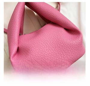 Detailed macro shot of rose pink litchi grain leather and pleated cloud bag texture