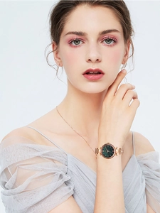 Detail of elegant women's rose gold watch with deep green dial and matching necklace
