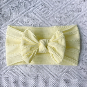 Detail of soft yellow knitted nylon baby headband with textured twist bow knot