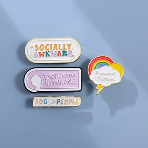 Set of four colorful enamel lapel pins with witty quotes on a clean blue surface