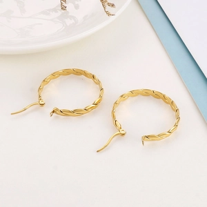 Close-up of gold-plated titanium steel hoop earrings featuring a twisted texture design