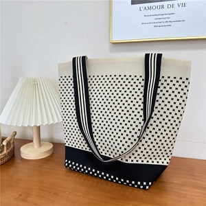 Detail of knitted houndstooth tote bag on wooden table with minimalist home decor style