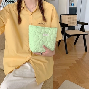 Close-up of quilted floral cosmetic bag in light green with 3D flower pattern and logo