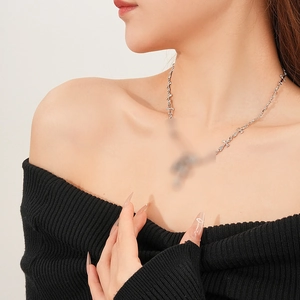 Detail of silver safety pin and cross link chain necklace worn on neck