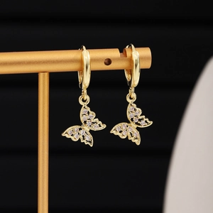 Macro shot of gold butterfly drop earring with pavé zircon detail on jewelry stand