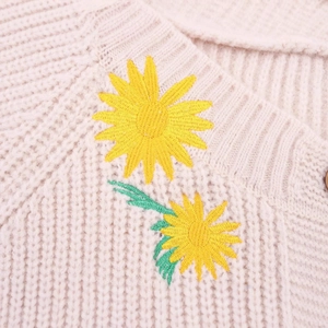 Oversized beige knitted cardigan featuring vibrant yellow sunflower embroidery detail