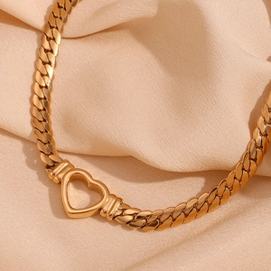 Close-up of 18K gold plated heart pendant on Cuban link chain over silk fabric