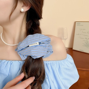 Close-up of blue and white striped fabric scrunchie on a braided hairstyle