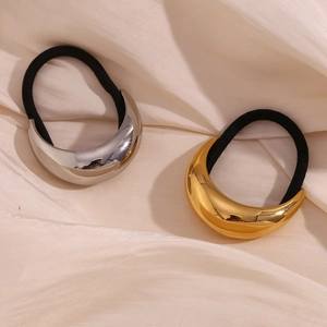 Close-up of gold and silver moon-shaped stainless steel hair ties on pink silk fabric