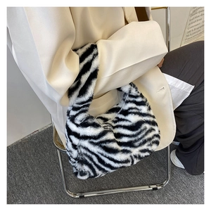 Chic women's zebra print plush tote bag shown with a neutral beige blazer outfit