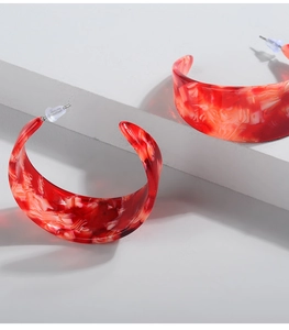 Macro detail of red marble texture on C-shaped resin earrings with silicone backings