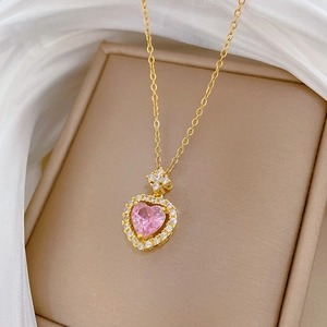Close-up of pink heart gemstone necklace with pavé diamonds on beige jewelry box