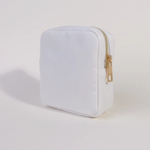 Detail view of a white nylon square makeup bag with a high-quality gold zipper closure