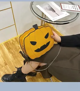 Detail of a pumpkin-shaped Halloween crossbody bag with gold chain strap worn by a model