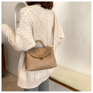 Khaki crossbody bag with gold lock shown from behind on a model wearing white sweater