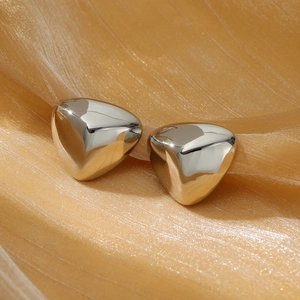 Macro shot of silver chunky triangular earrings on elegant gold pleated fabric