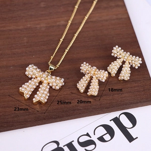Close-up detail of golden bow pearl jewelry set with size dimensions on wood surface