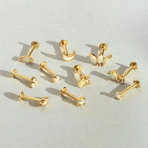 Flat lay of 14K gold opal flat back cartilage studs in moon and floral designs