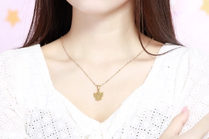 Dettaglio della collana dorata in acciaio inossidabile con ala d'angelo e lettera U