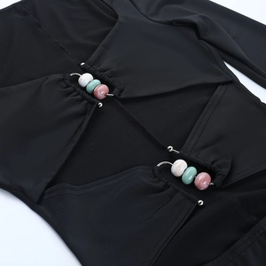 Dettaglio del vestito nero con ritagli e ciondoli in perline colorate e trama elastica
