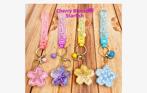Detail of four colorful cherry blossom starfishes keychains on a light wood background
