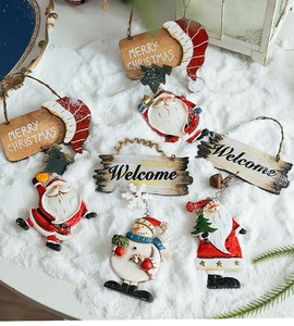 Flat lay of resin Santa and snowman ornaments with Merry Christmas signs on snow