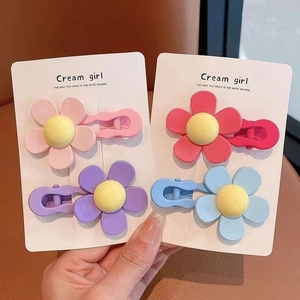 Detail of four colorful matte floral hair clips for girls on a white card display