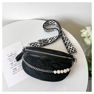Detail of black crossbody bag with pleated texture and decorative large white pearl chain
