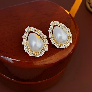 Detail of drop-shaped pearl earrings surrounded by trapezoidal zircons in gold finish