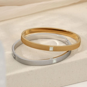Gold and silver minimalist stainless steel cuffs with mother of pearl insets on linen cloth