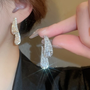 Close-up of silver zircon earrings with shimmering crystals and elegant curved design