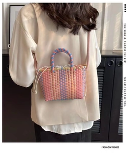 Detail of colorful woven straw bucket bag featuring a white drawstring and multi-color pattern