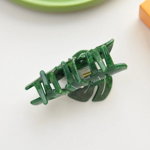 Detail of green monstera leaf hair claw clip with subtle glitter finish and spring