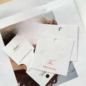Close-up of white cardboard jewelry display cards with custom logos and earring holes