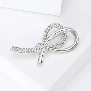 Close-up of a silver ribbon brooch featuring sparkling crystals on a geometric stand