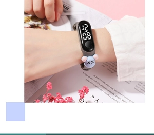 Detail of grey LED digital wristband with light blue cartoon bear charm on model's wrist