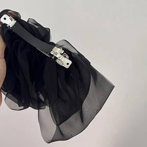 Detail of black multi-layered chiffon bow hair clip showing spring clip and sheer texture